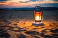 an illuminated camping lantern in sand at dusk