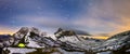 Panaorma of illuminated tent under starry night sky in snowy alpine mountains. Alps, Switzerland.