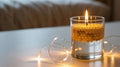 Illuminated candle in glass with yellow beads and string lights nearby Royalty Free Stock Photo