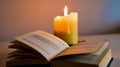 Illuminated candle with melted wax and open book on a flat surface Royalty Free Stock Photo