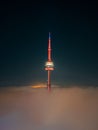 Illuminated CN tower stands tall in the midst of a foggy landscape