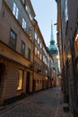 Illuminated cobbled street in the old town of Stockholm, Sweden at dusk with a church at the end
