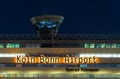 Illuminated Cologne Bonn Airport sign with the air traffic tower at night