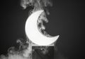 Illuminated crescent moon object emerging from wisps of smoke against a dark background Royalty Free Stock Photo