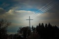 illuminated cross against a blue sky surrounded by trees Royalty Free Stock Photo