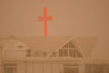 Illuminated cross of a Korean church under a dense haze formed by airborne dust.