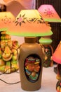 An illuminated decorative handmade table lamp is displayed in a street shop for sale. Indian handicraft and art