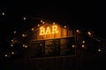 Illuminated glowing BAR sign on a wooden kiosk at a Christmas market