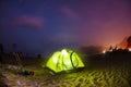Illuminated green camping tent under stars at night