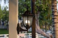 Illuminated hanging lantern lamp light on concrete pole post in the garden in the evening.