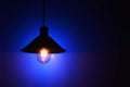 Illuminated hanging led light bulb over blue background Royalty Free Stock Photo