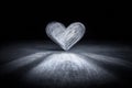 Illuminated heart shape casting shadows on textured ground in a dark, minimalistic setting Royalty Free Stock Photo