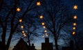 Illuminated Herrnhuter Moravian Christmas stars hanging above the dark silhouettes of old house gables and big trees against a Royalty Free Stock Photo