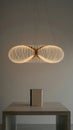Illuminated infinity loop pendant lamp hangs above a table with a book light, Generated with AI Royalty Free Stock Photo