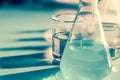 Illuminated laboratory flask filed with colorful chemical solutions with shadows on the table. Laboratory, science