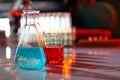 Illuminated laboratory flask filed with colorful chemical solutions with shadows on the table. Laboratory, science