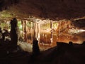 Illuminated lake inside of a dripstone cave.