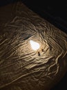 Illuminated lamp on textured fabric background, dim lighting. Soft shadow and warm glow Royalty Free Stock Photo