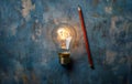 Illuminated Light Bulb and Pencil on Rustic Background Royalty Free Stock Photo