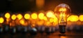 Illuminated light bulb standing out among blurred background of glowing bulbs, copy space for text Royalty Free Stock Photo