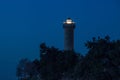 Illuminated lighthouse in Savudrija, Istria, Croatia with silhouettes of trees at night Royalty Free Stock Photo