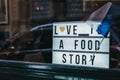 Close up of illuminated `Love is a food story` sign in a window of a restaurant