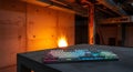 Illuminated mechanical keyboard rests on a concrete table with industrial background and fire effect Royalty Free Stock Photo
