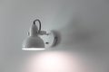 Illuminated metal white electric lamp on gray wall