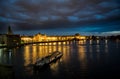 Illuminated Moldova River With Ship And Historic Buildings In The Night In Prague In The Czech Republic