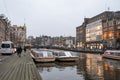 Illuminated moody Amsterdam canals view,touristic boats,traditional architecture