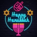 Illuminated neon signs Happy Hanukkah holiday light electric banner glowing on black brickwall.