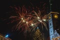 Illuminated night sky displaying a vibrant fireworks show over a city skyline of buildings and roads