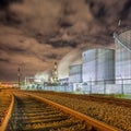 Night scene with illuminated petrochemical production with large silos and rails Royalty Free Stock Photo