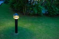 Illuminated outdoor light in apartment garden at twilight, evening.