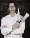 Illuminated portrait of nice and attractive man chef in uniform on the stone wall background. Man chef posing to camera with knif Royalty Free Stock Photo