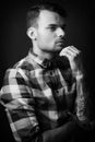 Illuminated portrait of young thoughtful man on black background. Dark photo portrait of thinking male tattooed fashion model