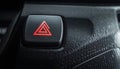 Illuminated red hazard light button on a dark car dashboard with textured surface Keywords: car, dashboard, hazard Royalty Free Stock Photo