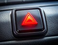 Illuminated red hazard light button with a triangle symbol on a car dashboard image photo Royalty Free Stock Photo