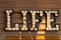 Illuminated sign LIFE on a wooden wall