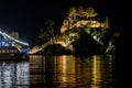 Illuminated Small Island with a Boat Anchored in Tranquil Bay in Parga, Greece, at Night. Calm Sea Waters Reflect the Lights Royalty Free Stock Photo