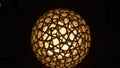 Illuminated sphere with woven pattern casting light and shadows in a dark environment indoors Royalty Free Stock Photo