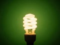 Illuminated spiral bulb on green background Royalty Free Stock Photo