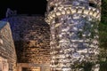 Illuminated stone castle wall and tower at night Royalty Free Stock Photo