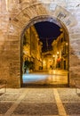 Illuminated street with historic fortification wall gate at old town of Alcudia on Majorca, Spain