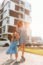 Illuminated by sunlight. Young mother with her little daughter walking near the buildings Royalty Free Stock Photo