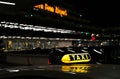 Illuminated taxi sign of a waiting cab at the airport at night with a blurred background. Royalty Free Stock Photo