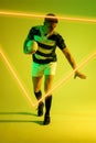 Illuminated triangle over caucasian male player with rugby ball standing over gradient background