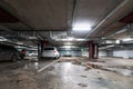 Illuminated underground car parking garage interior under modern mall with lots of vehicles