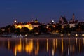 Illuminated Warsaw Old Town landscape with the Royal Castle, Cathedral and medieval buildings, night view with reflections in calm