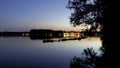 Illuminated waterside of a lake with trees and rocks in colorful dusk time lapse